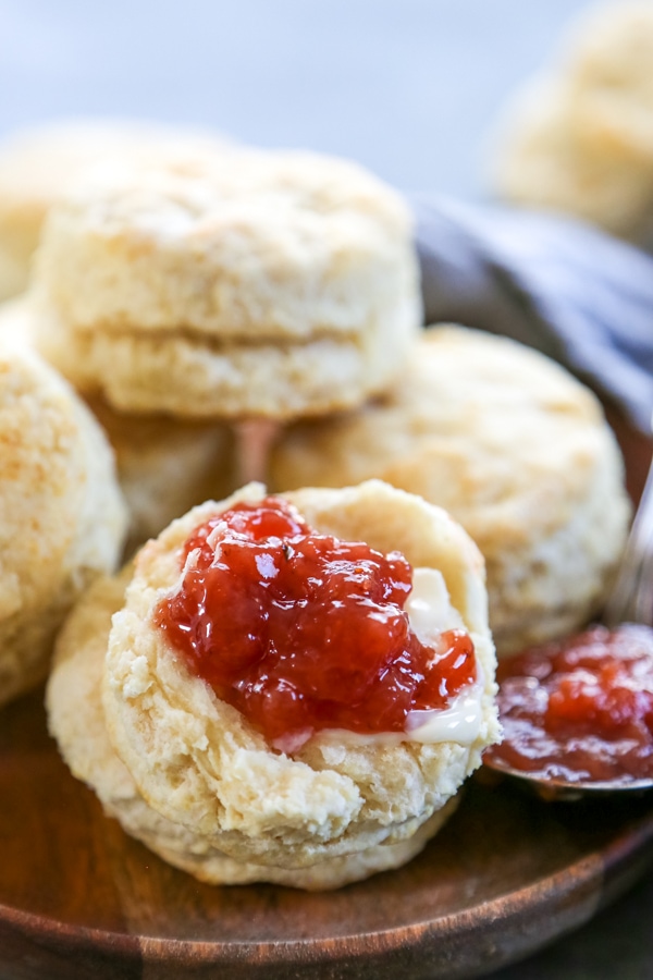 close up of a sliced biscuit topped with butter and jam.