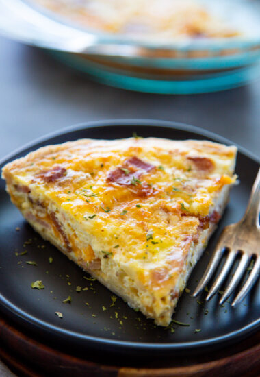 a slice of quiche on a plate with a fork.