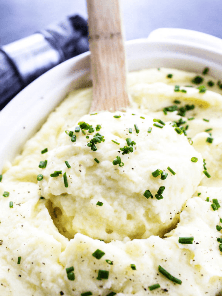 Creamy Mashed potatoes in serving dish with wooden spoon