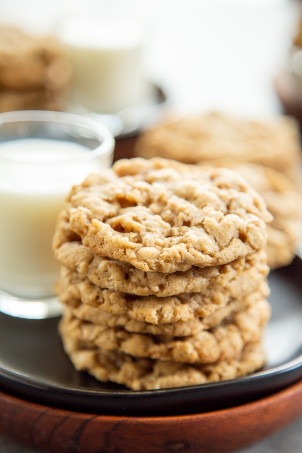 a stack of oatmeal cookies on a plate with a glass of milk.