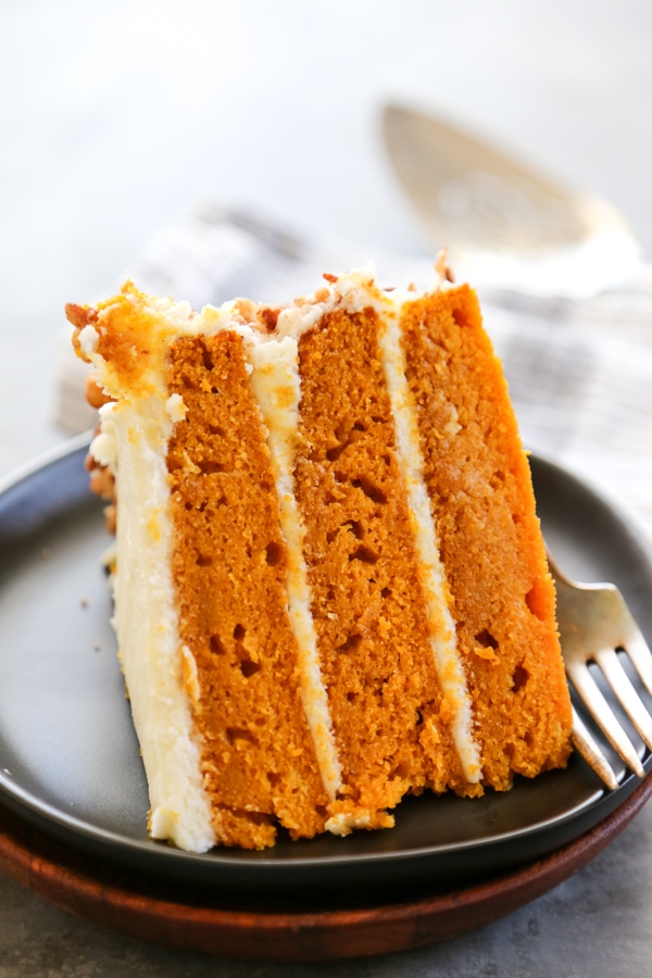 a sliced of frosted cake on a plate with a fork.