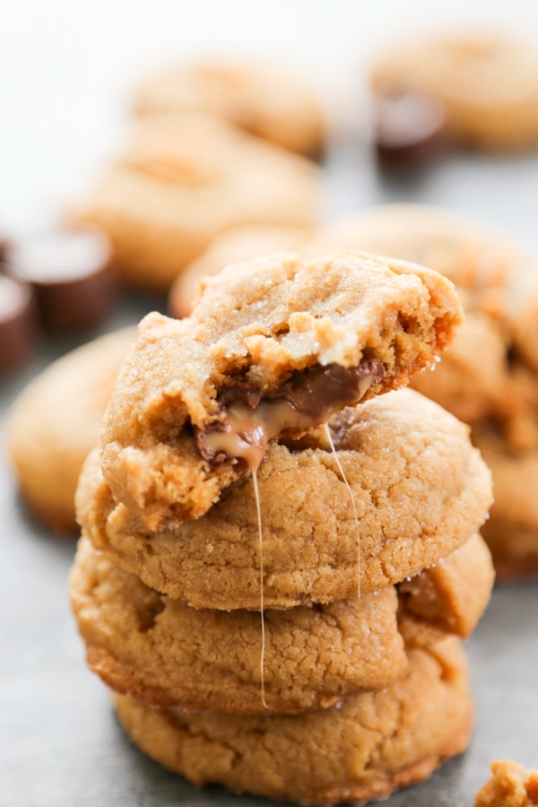 a stack of cookies with the top one oozing chocolate and caramel.