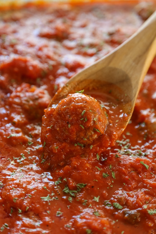 close-up shot of meatballs simmering in a pan with marinara sauce.