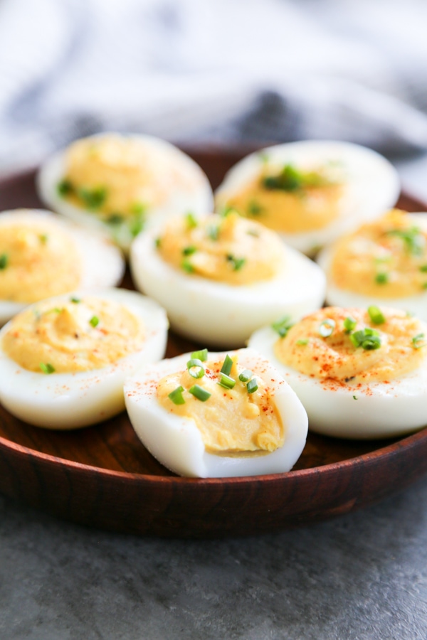 wooden plate with deviled eggs on it with bite of out of the deviled eggs