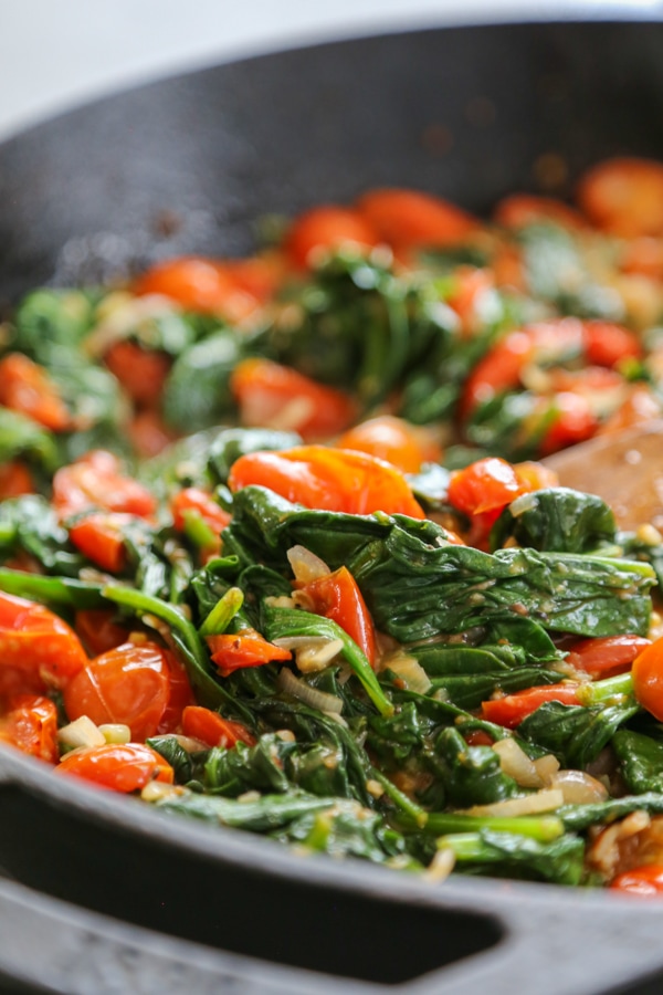 the cooked tomatoes and spinach in a pan.