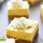 close up shot of a key lime pie bar topped with whipped cream and zest.