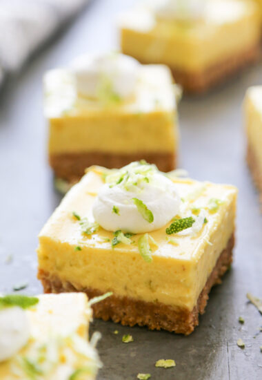 close up shot of a key lime pie bar topped with whipped cream and zest.