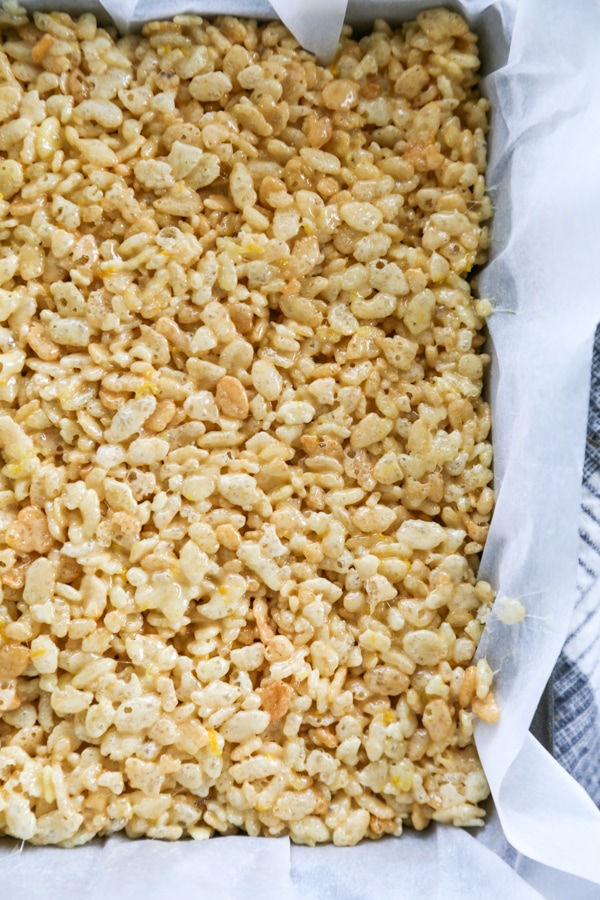 overhead shot of the cereal marshmallow mixture pressed into a baking dish.