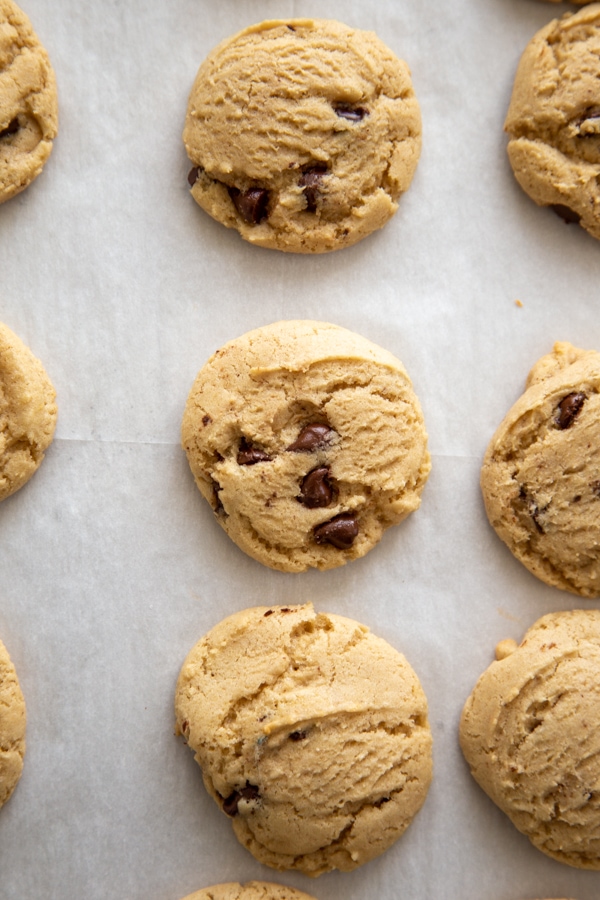 overhead shot of chocolate chip cookies on a baking sheet with parchment paper