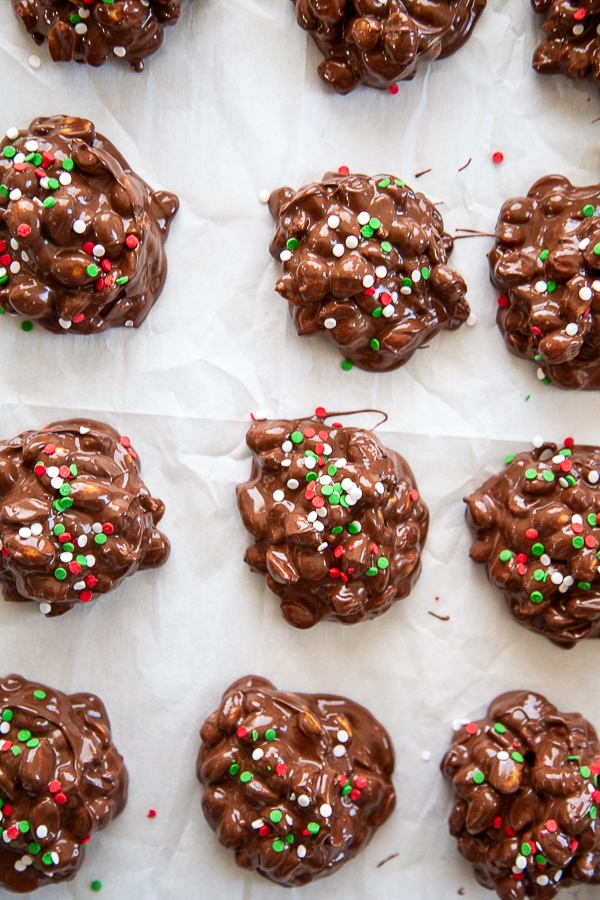 chocolate peanut clusters stack with Christmas sprinkles overhead shot on parchment paper