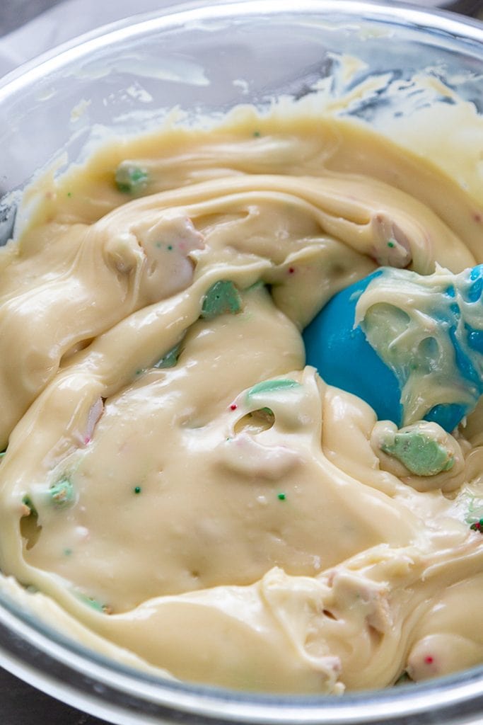 white chocolate fudge in bowl mixing in christmas cookies