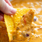 close up shot of chip dipped in chili cheese dip