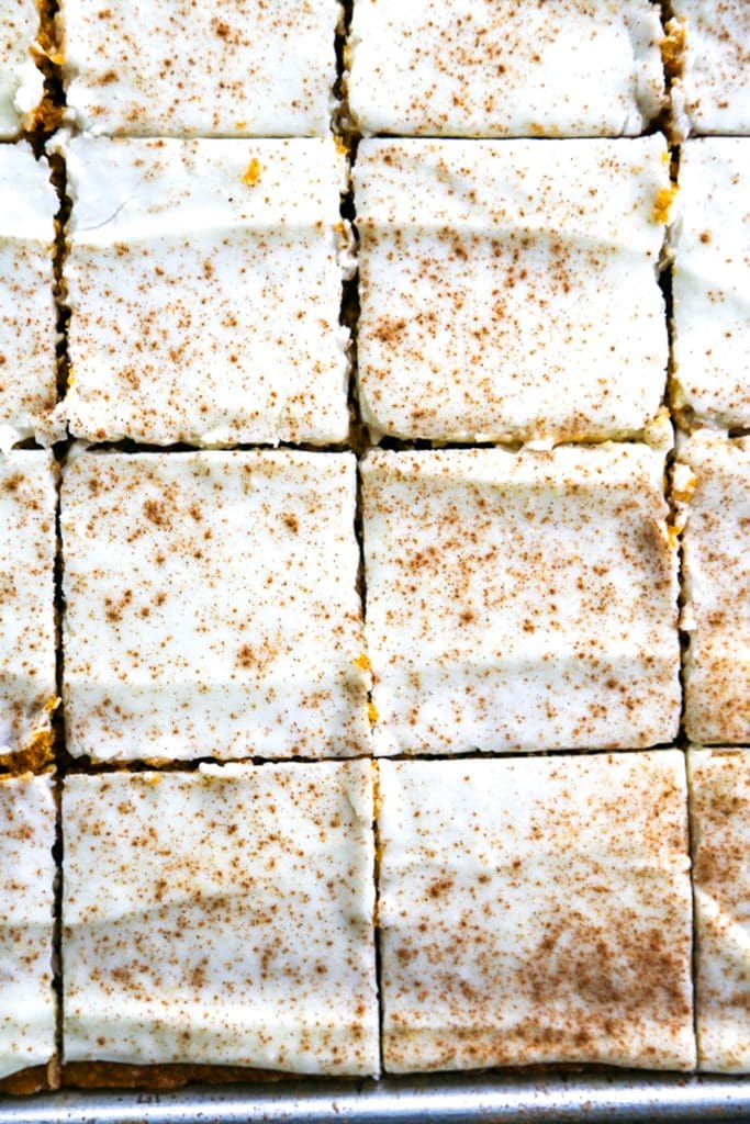 overhead shot of frosted pumpkin bars in baking sheet and sliced