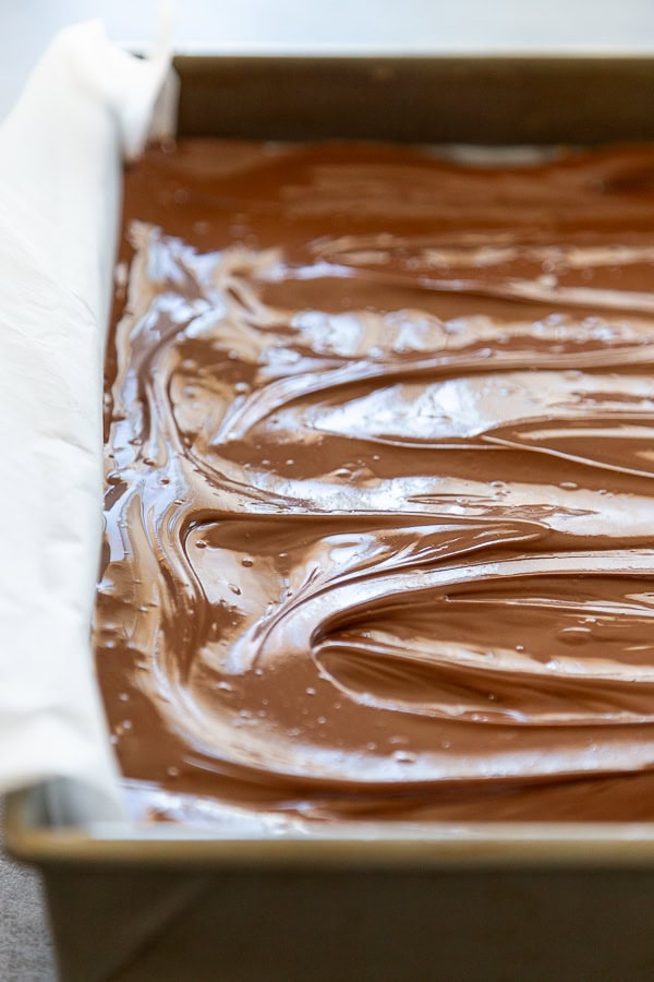 melted chocolate spread over bars in 9x13 metal pan