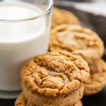 stack of peanut butter cookies next to a cup of milk