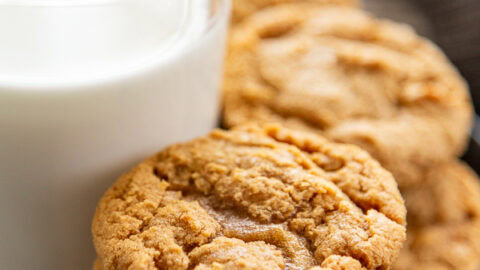 stack of peanut butter cookies next to a cup of milk