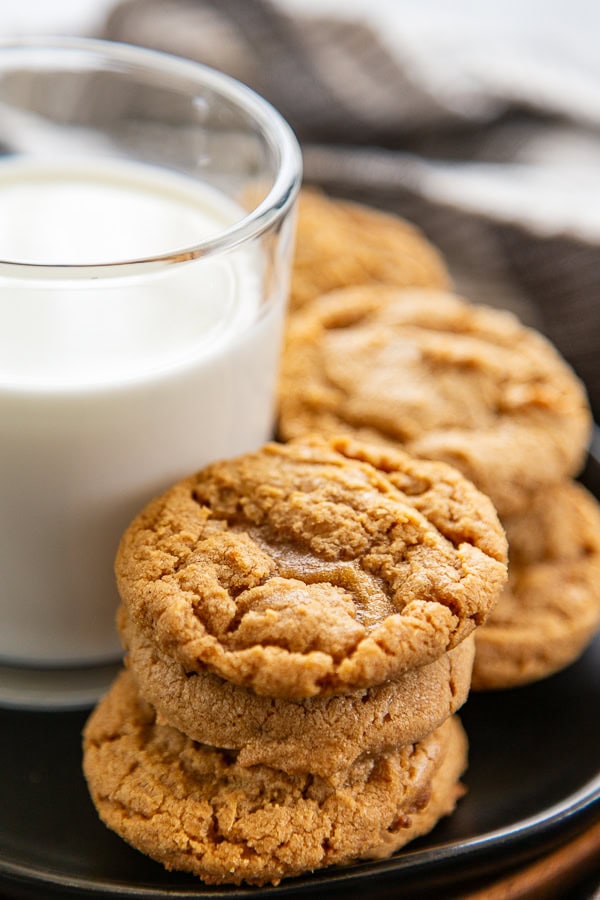 stack of peanut butter cookies next to a cup of milk