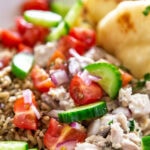 bowl of lemon chicken, naan and fresh cucumbers, tomatoes and onion