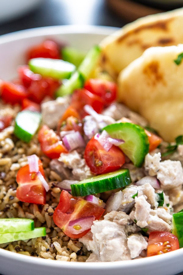 bowl of lemon chicken, naan and fresh cucumbers, tomatoes and onion