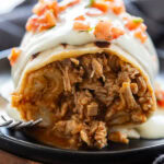close up shot of chicken burrito covered in white sauce