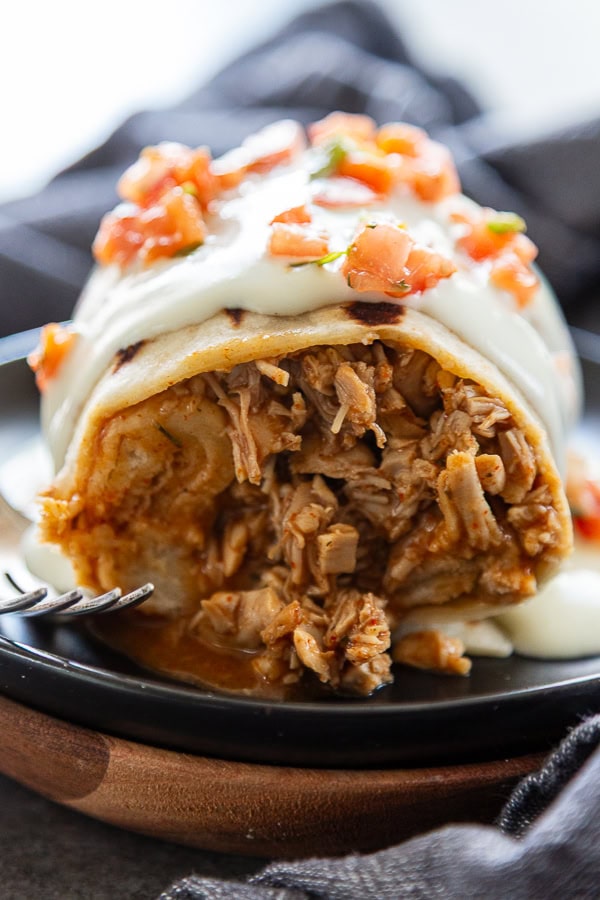 close up shot of chicken burrito covered in white sauce